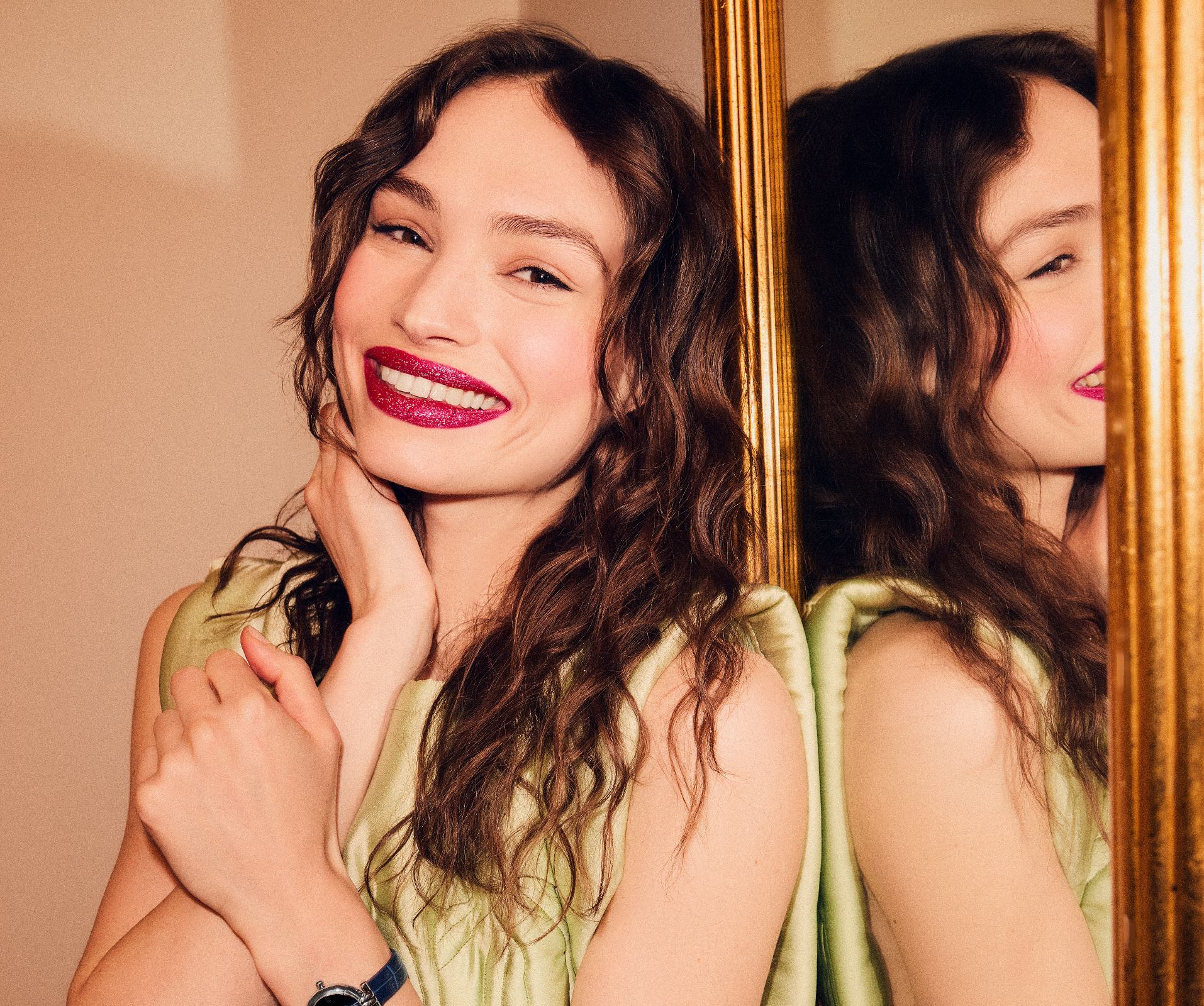 a woman smiling and touching her face