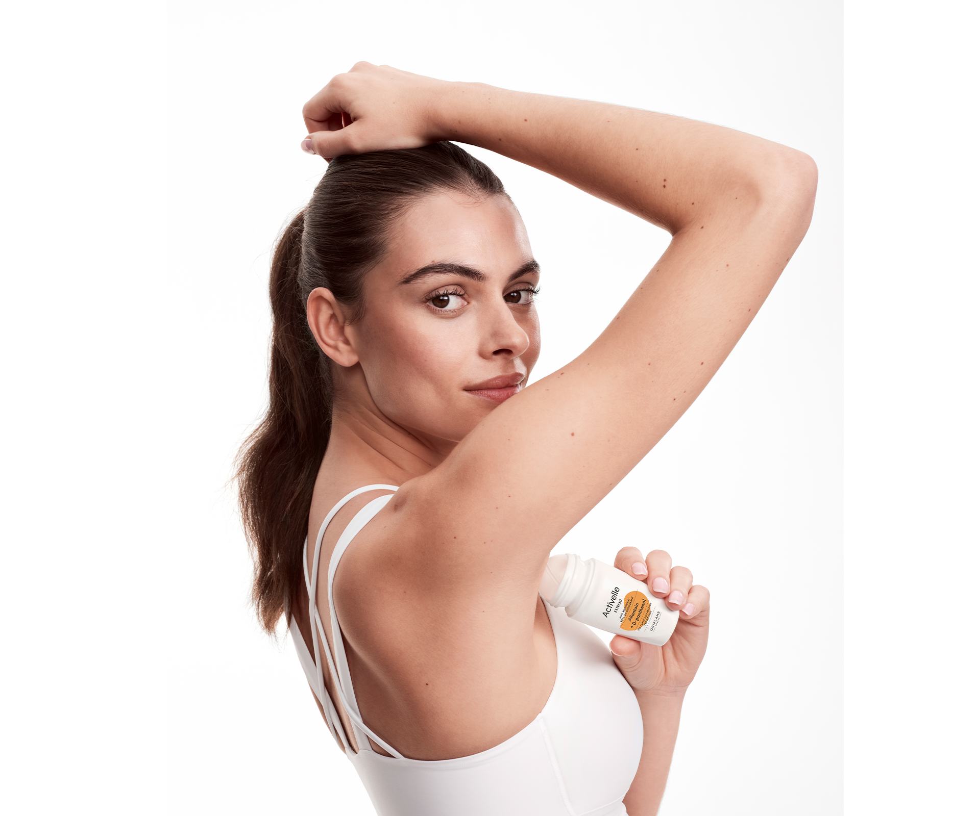 a woman in a white tank top holding a bottle of deodorant