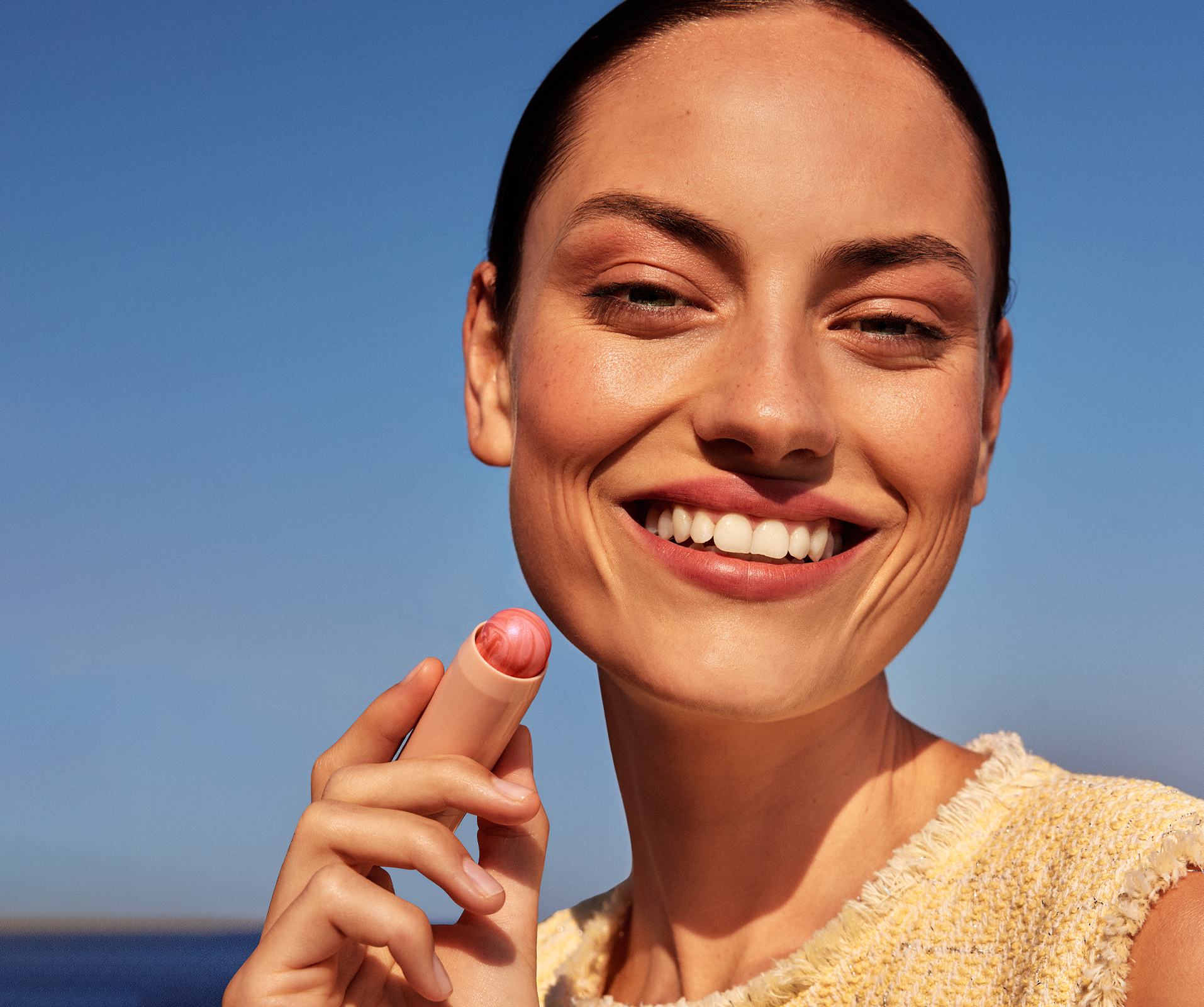 a woman smiling holding a lipstick