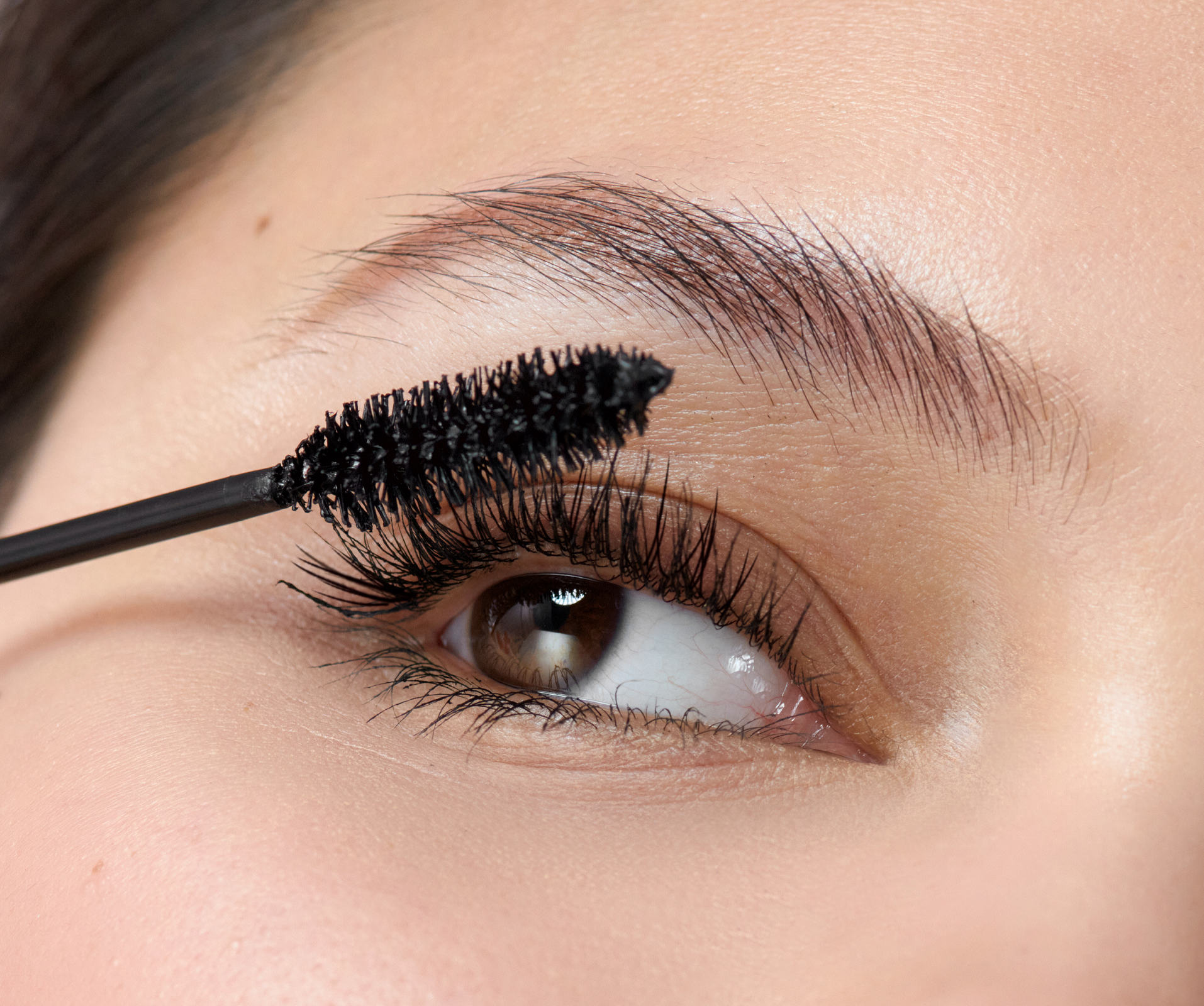 une femme en train d’appliquer du mascara sur ses yeux