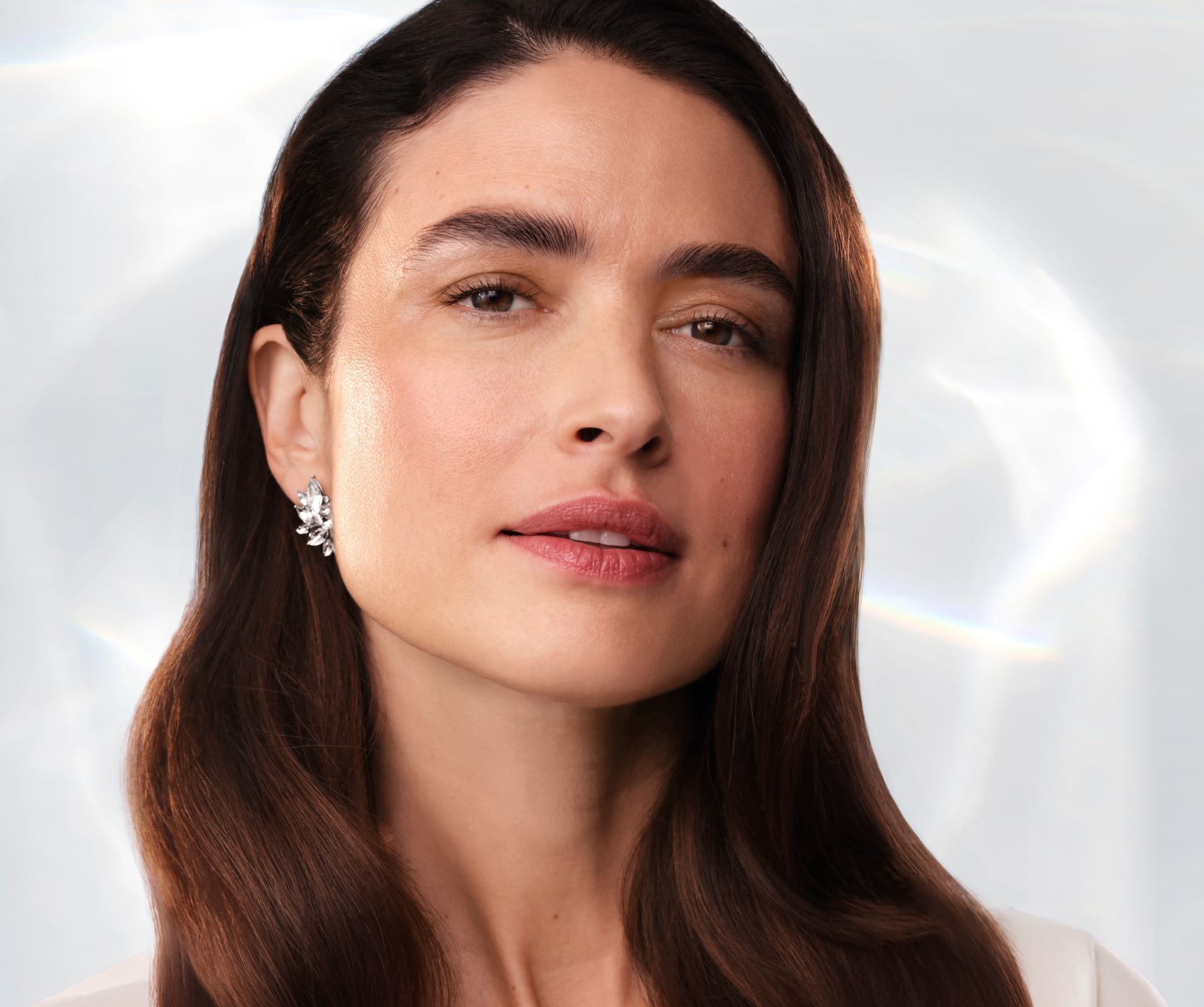a woman with long brown hair and a diamond earring
