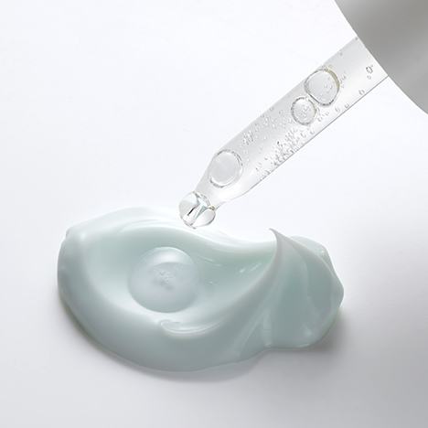 Un gotero que gotea líquido en una crema blanca.