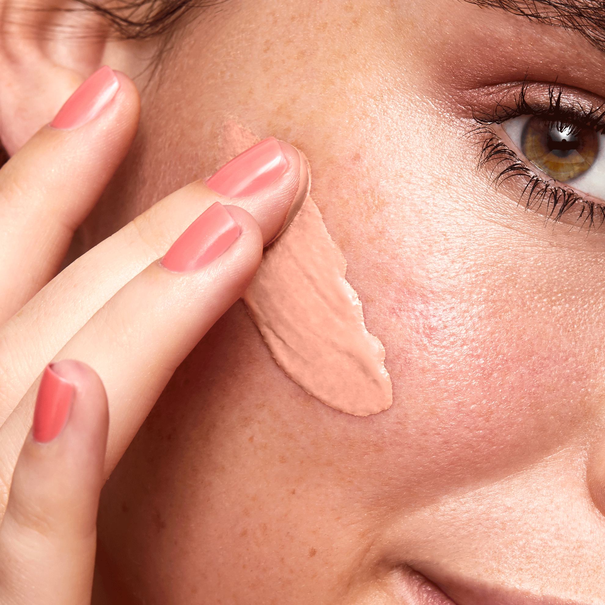 a close up of a woman applying foundation on her face
