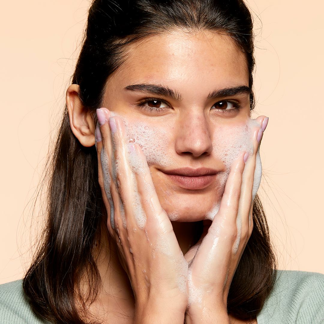 Una mujer lavándose la cara.