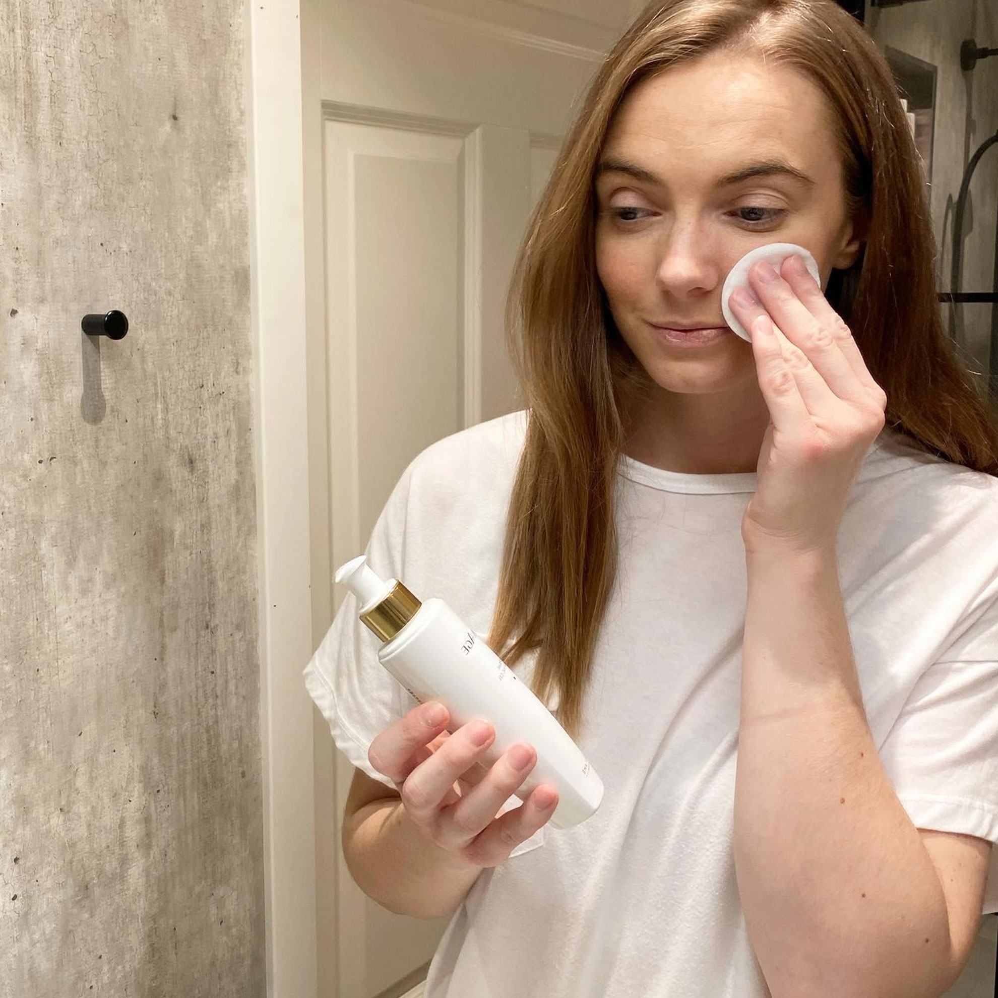 en kvinne bruker en bomullspad til å fjerne ansiktssminke