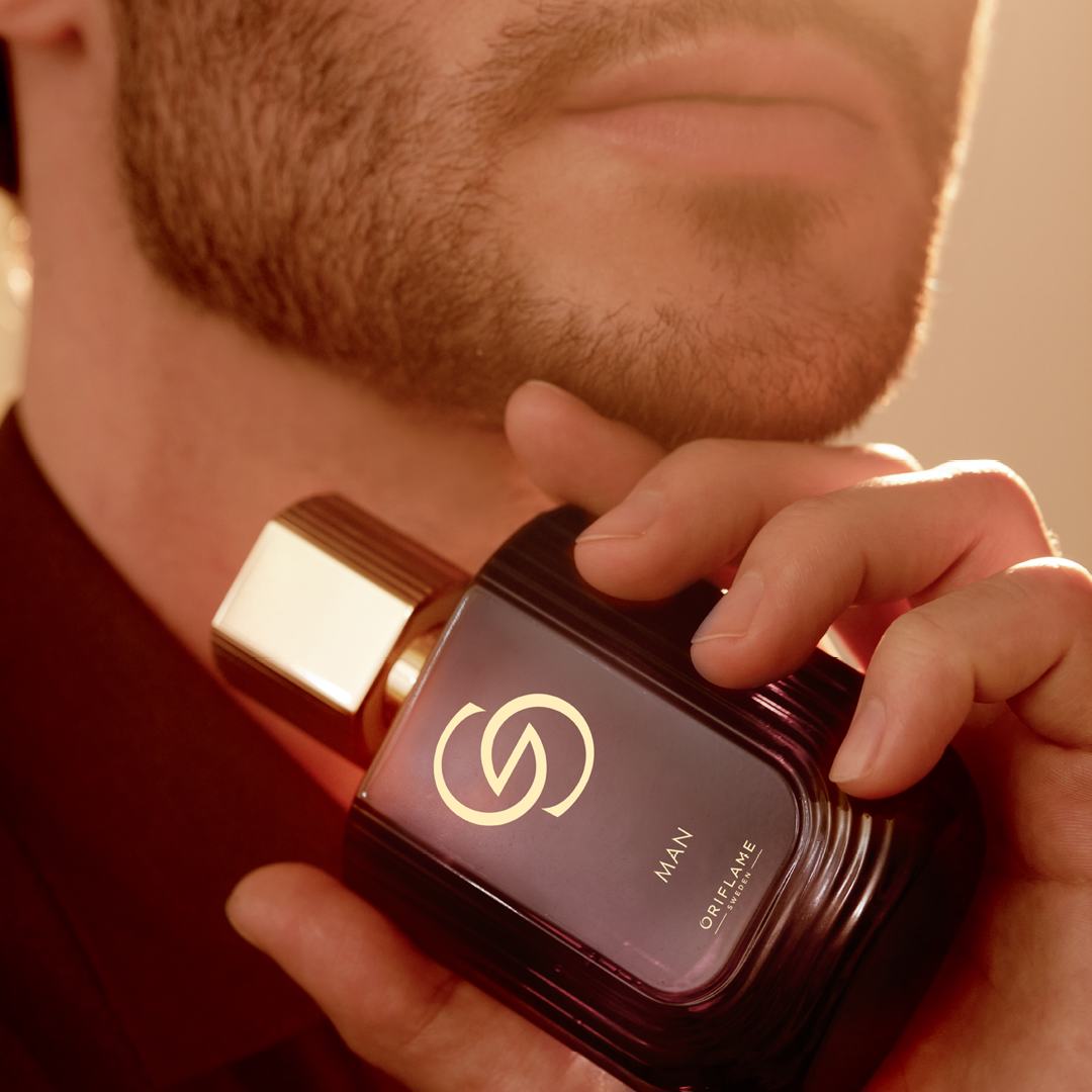 un bărbat ținând o sticlă de parfum