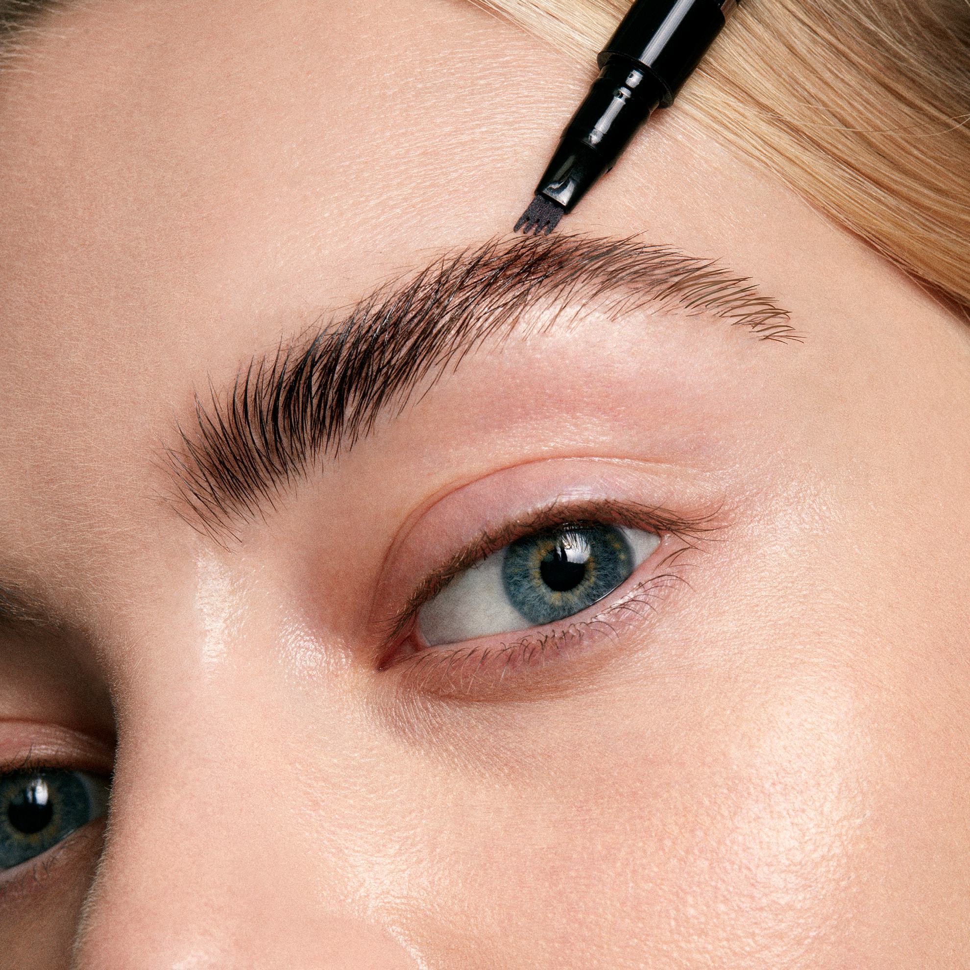 a woman applying a black eyebrow brush