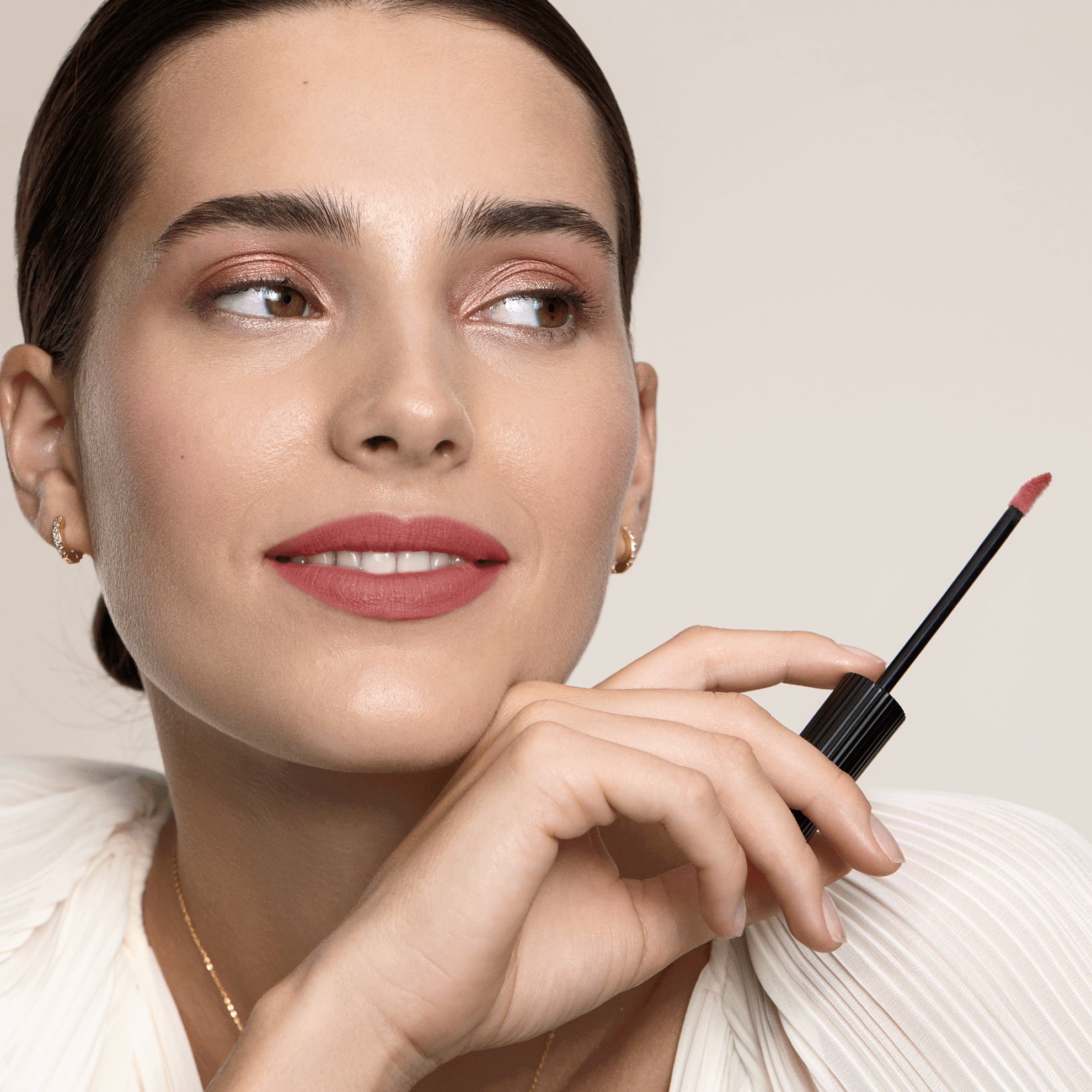 Una mujer sosteniendo un brillo de labios