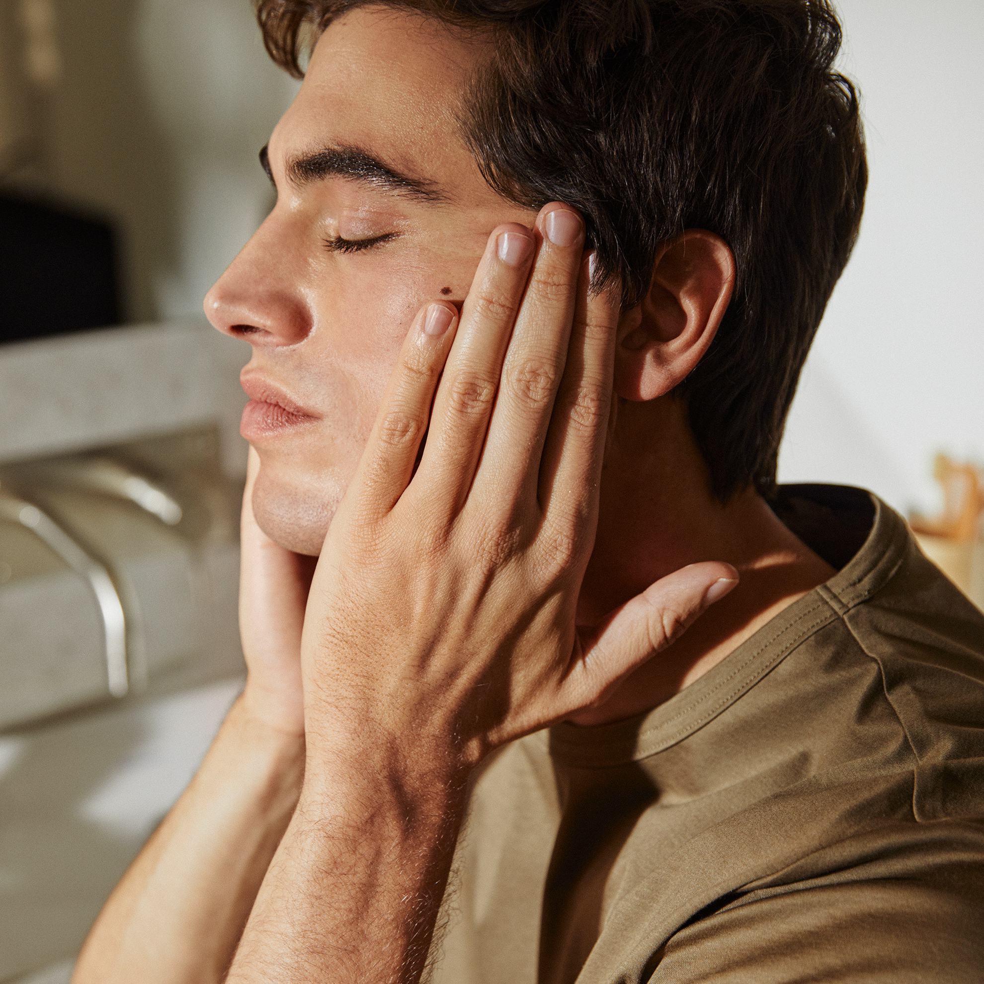 vyras, laikantis rankas ant veido