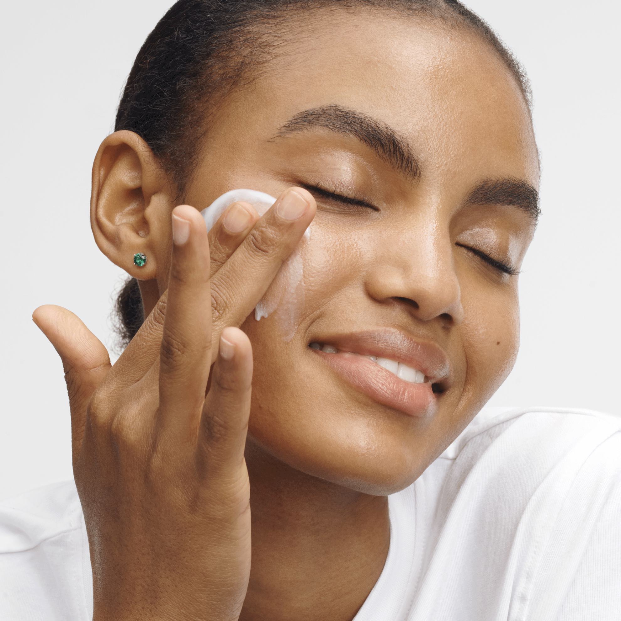 женщина наносит крем на лицо