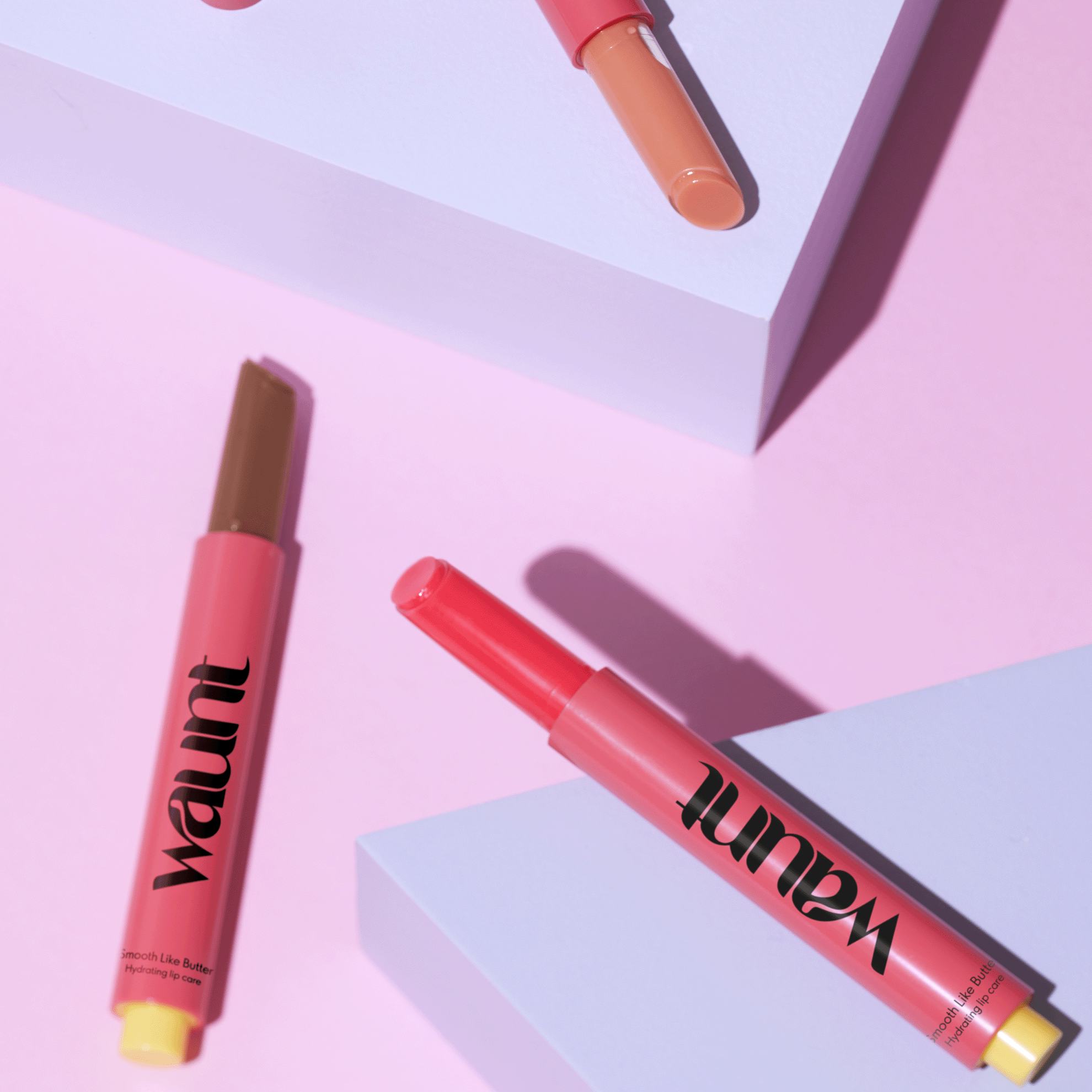 een groep lippenstiften op een roze ondergrond