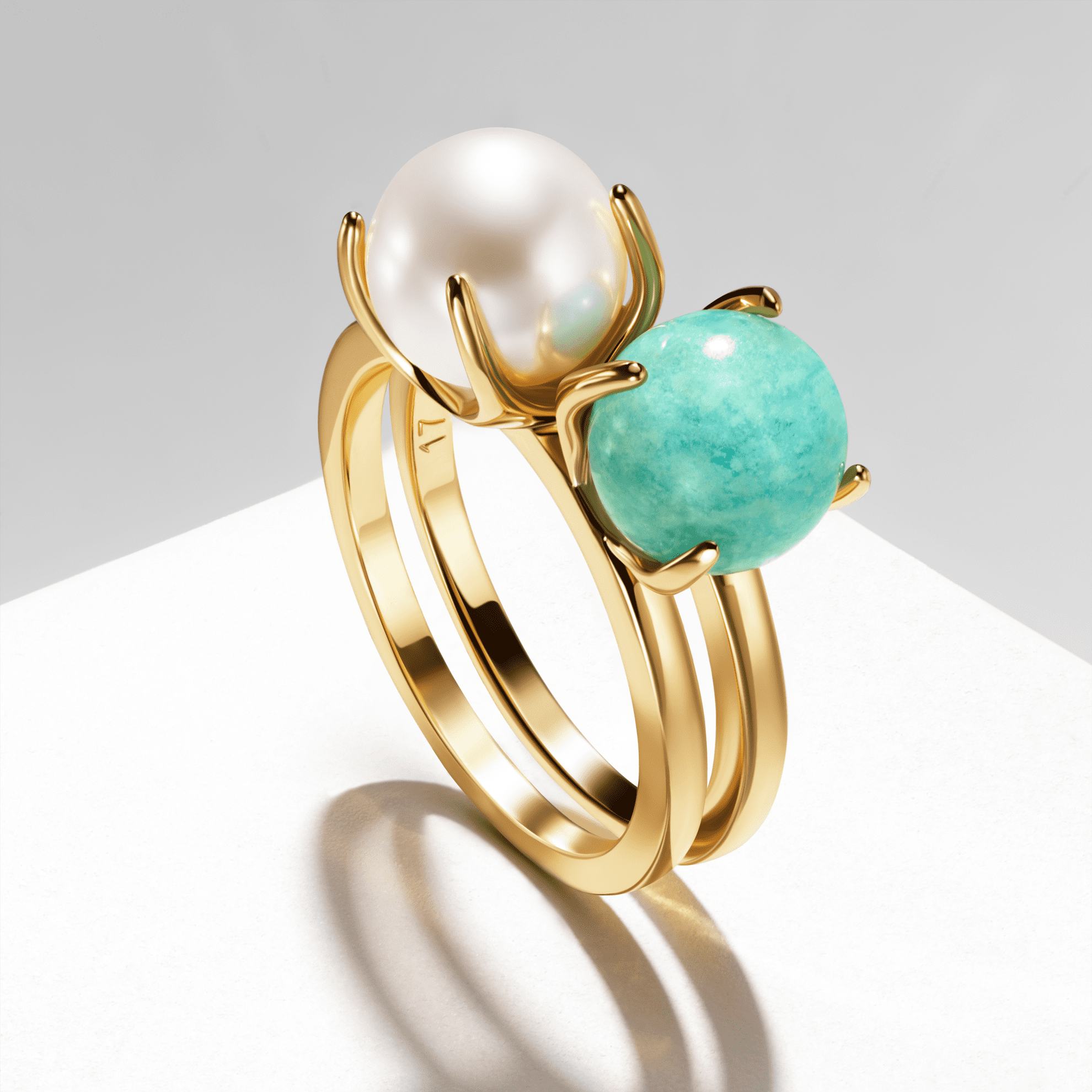 Un anillo de oro con una perla y una piedra azul.