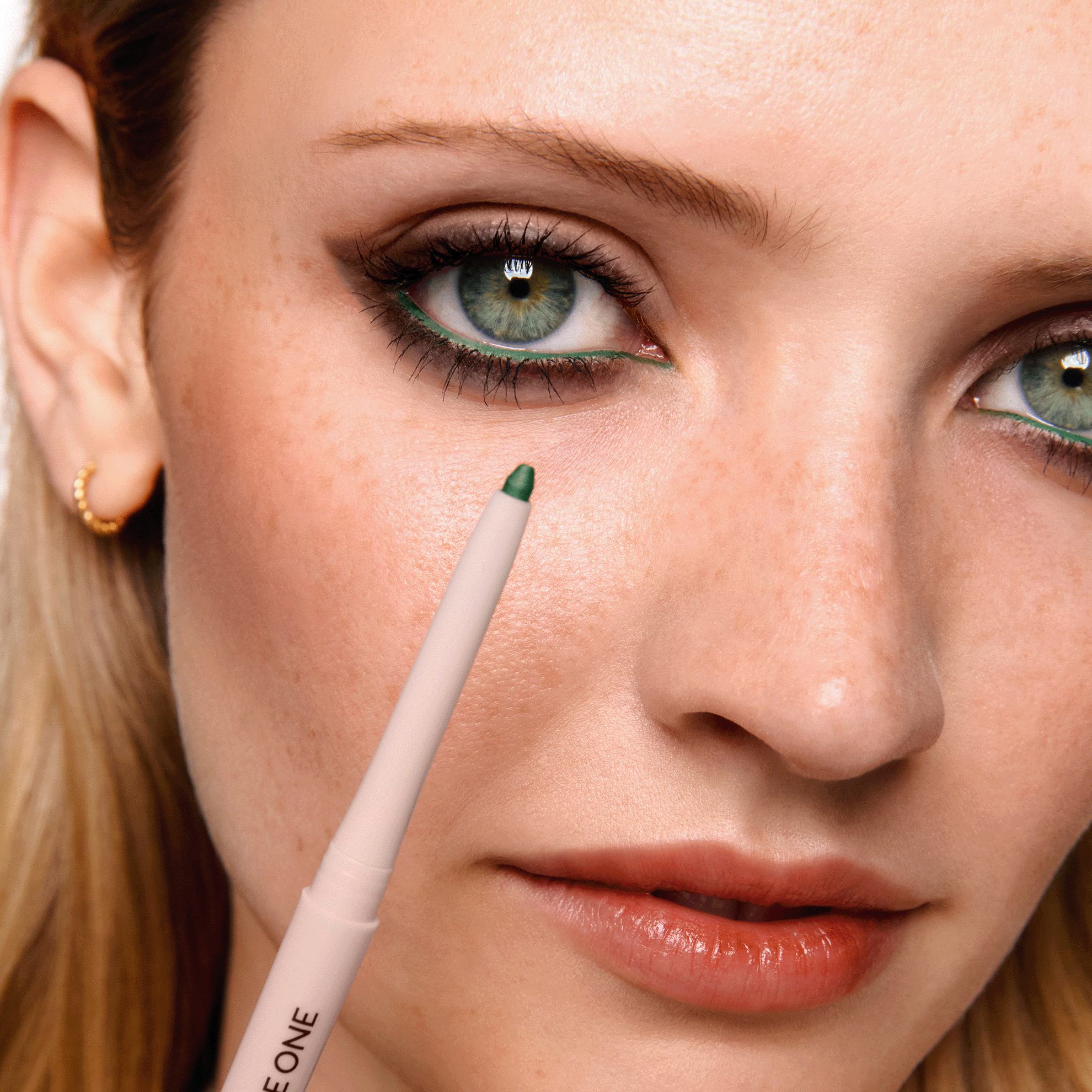 yeşil göz kalemi tutan bir kadın