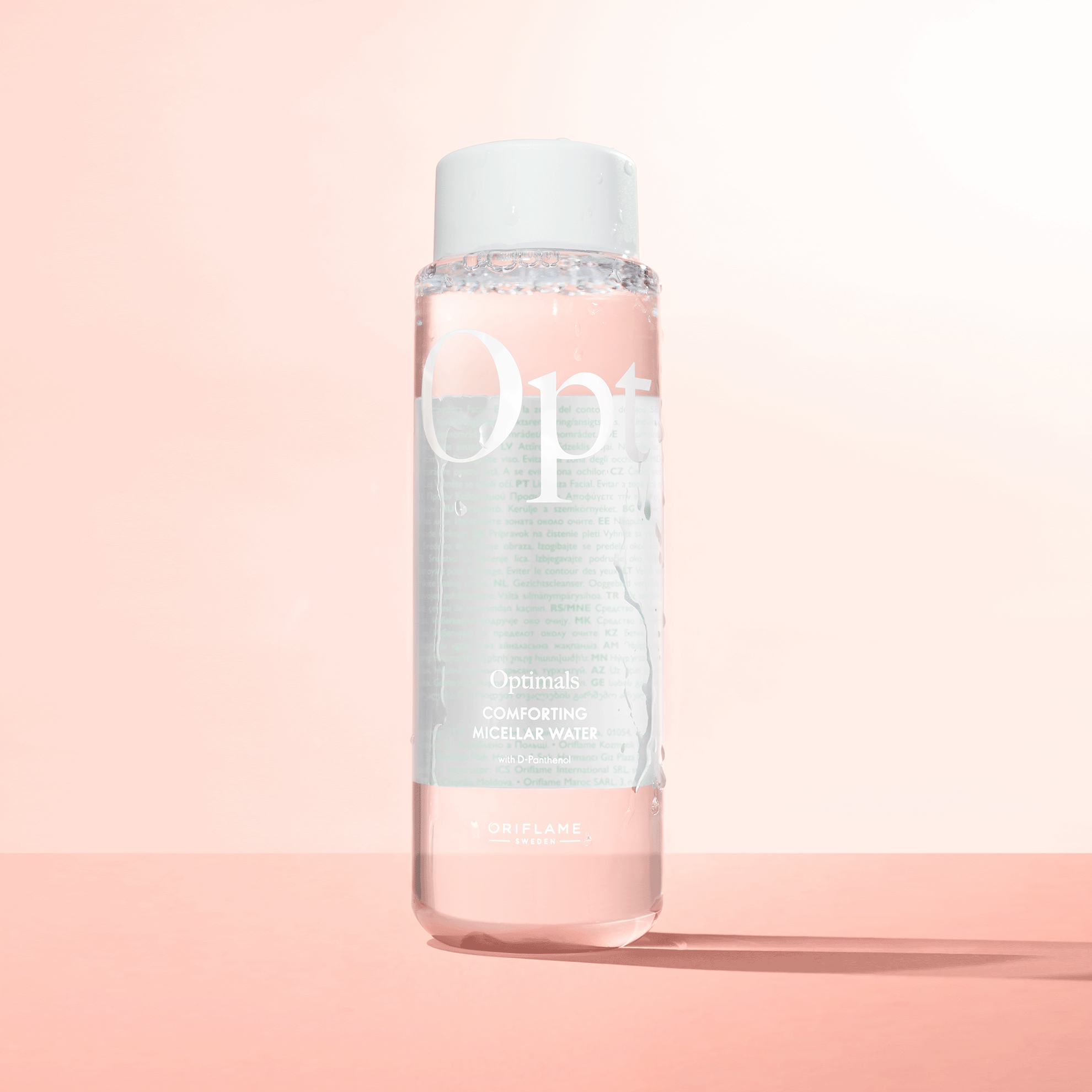 o sticlă cu lichid pe o suprafață roz