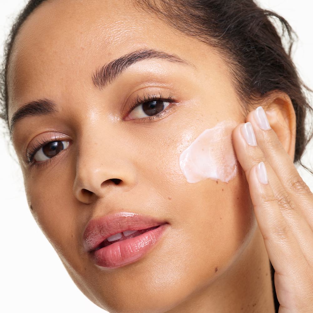 ženska, ki si na obraz nanaša kremo