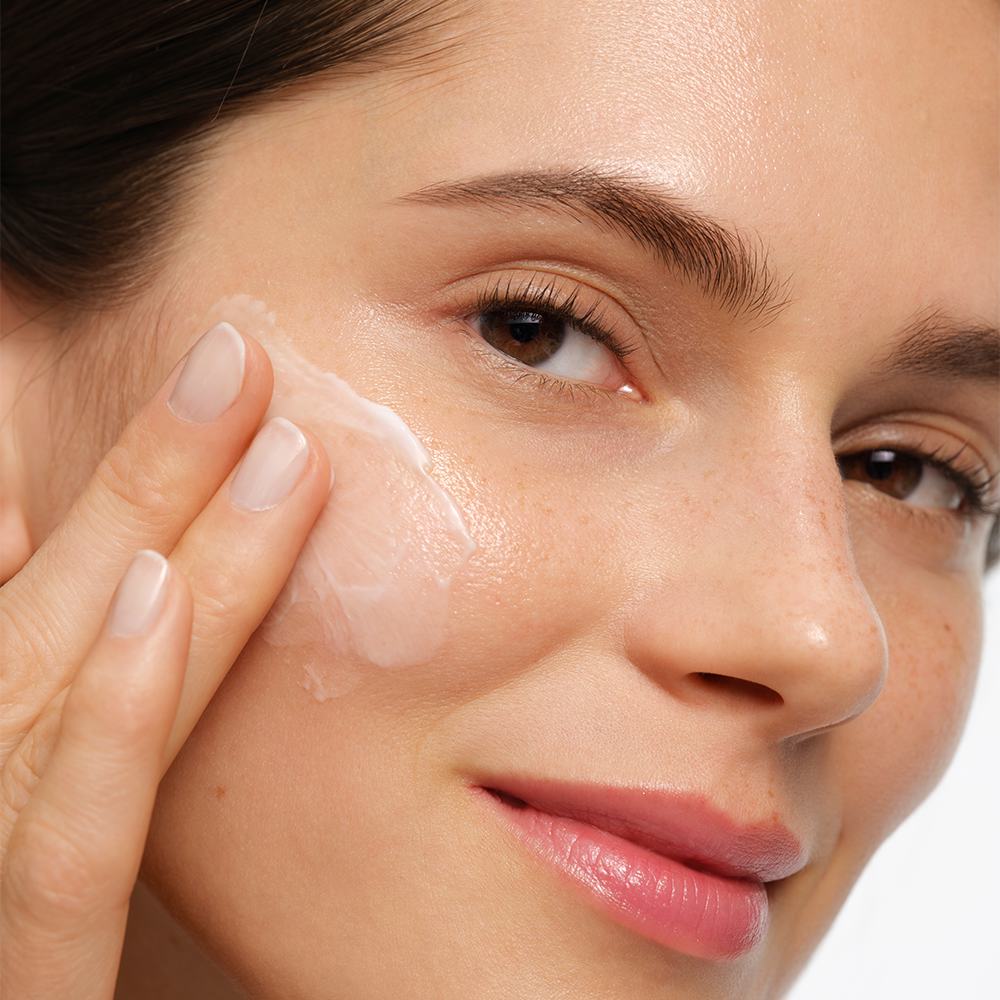 ženska, ki si nanaša kremo na obraz