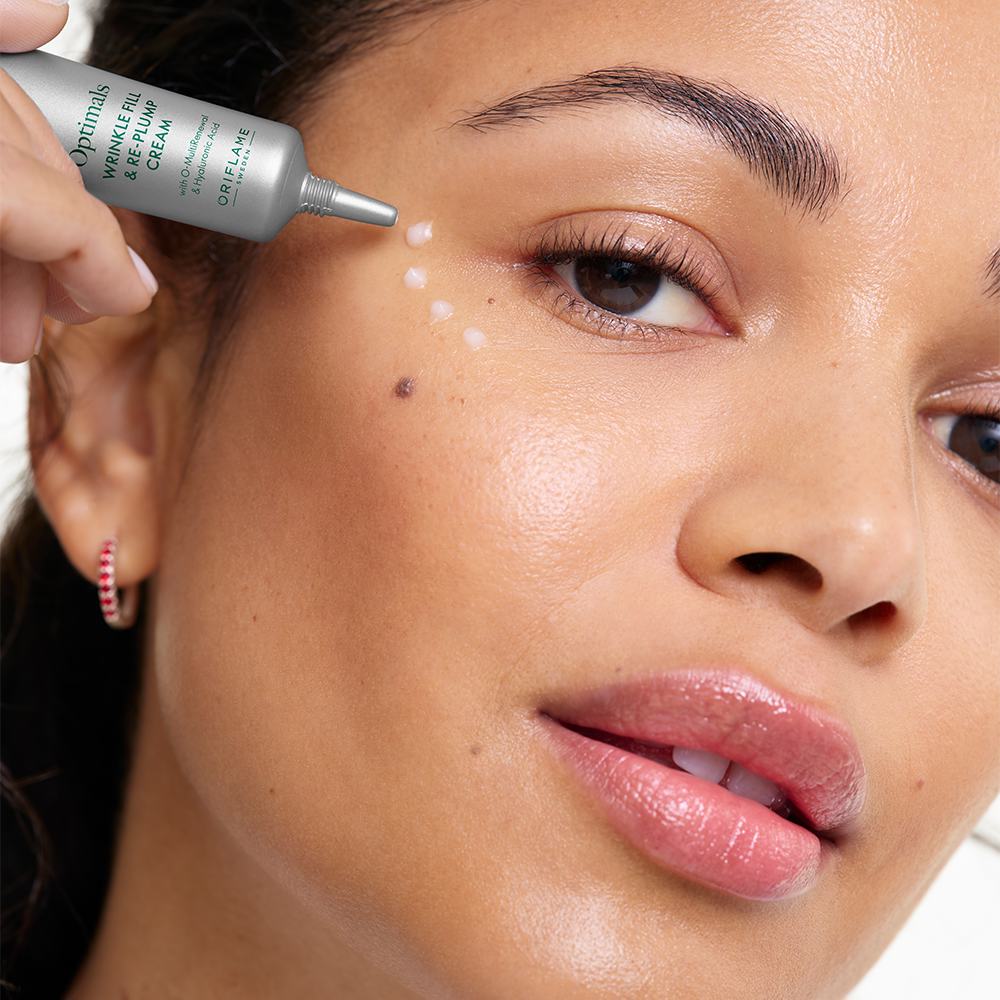 ženska, ki si na obraz nanaša kremo