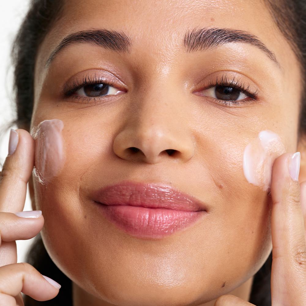 ženska, ki si nanaša kremo na obraz
