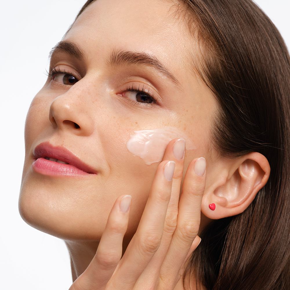 ženska, ki si nanaša kremo na obraz