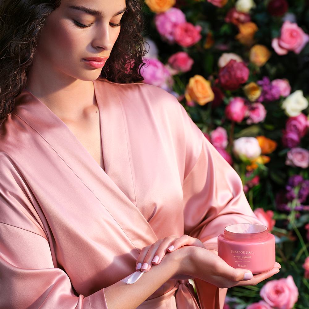 жена в розова роба, държаща розов буркан с крем