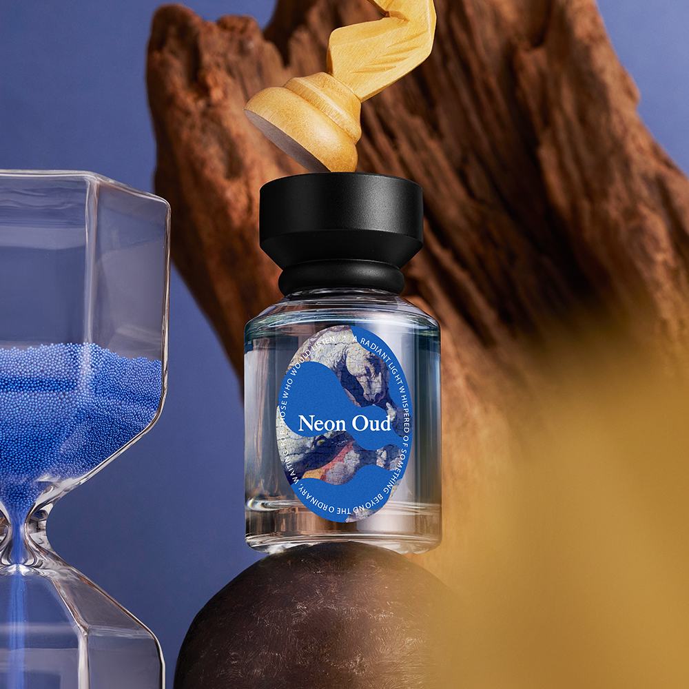 een glazen fles met een gouden voorwerp erop en een glas met blauw zand