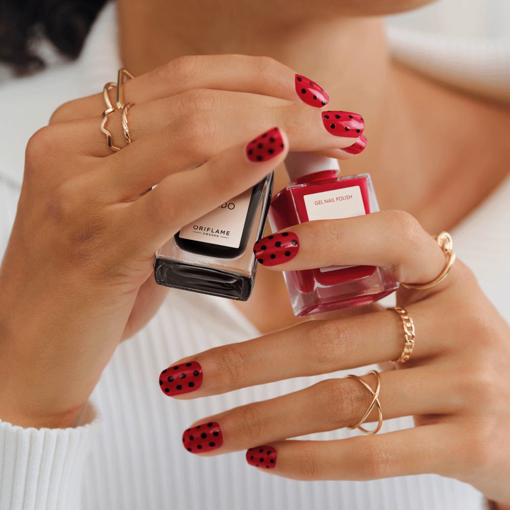 nainen, joka pitää kädessään kynsilakkapulloa