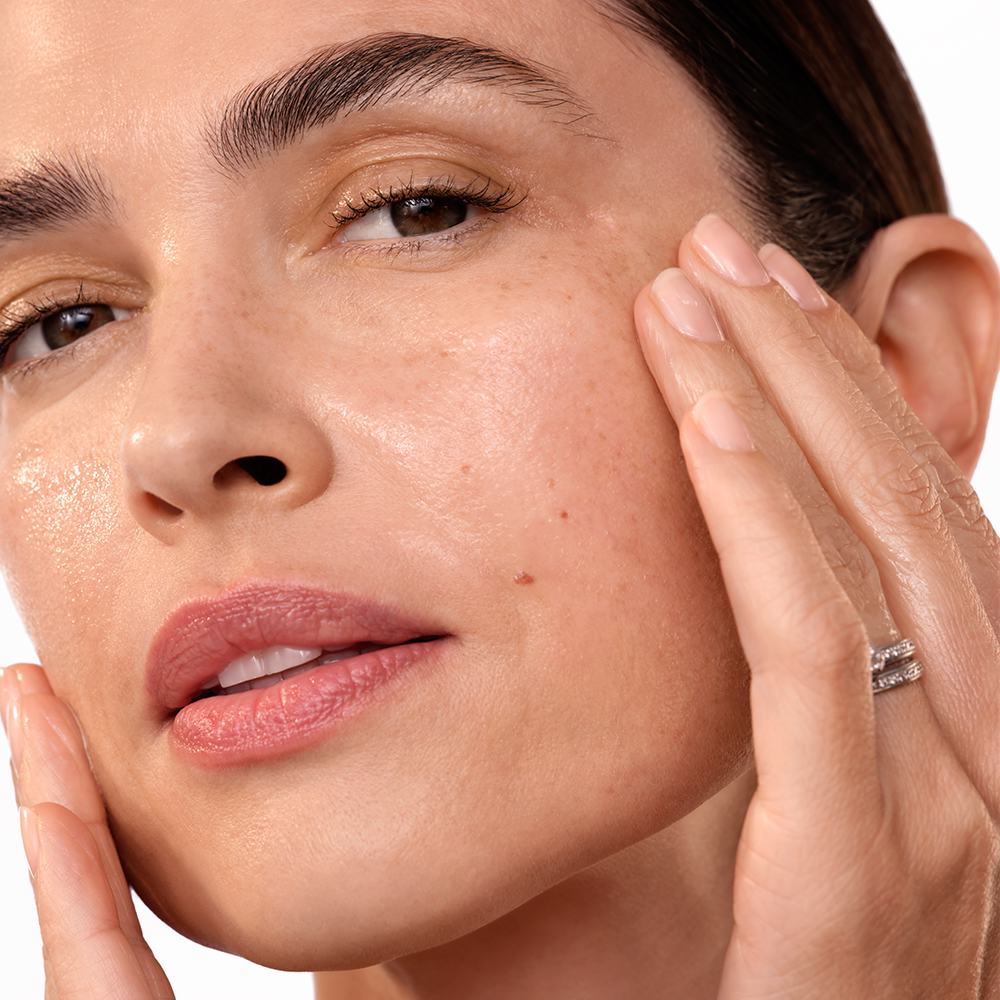 en kvinna som rör vid sitt ansikte