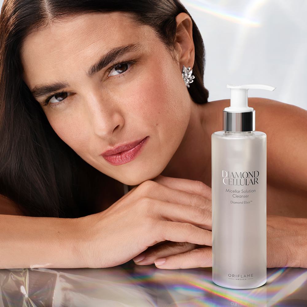 en kvinna som lutar sig mot ett bord med en flaska vätska