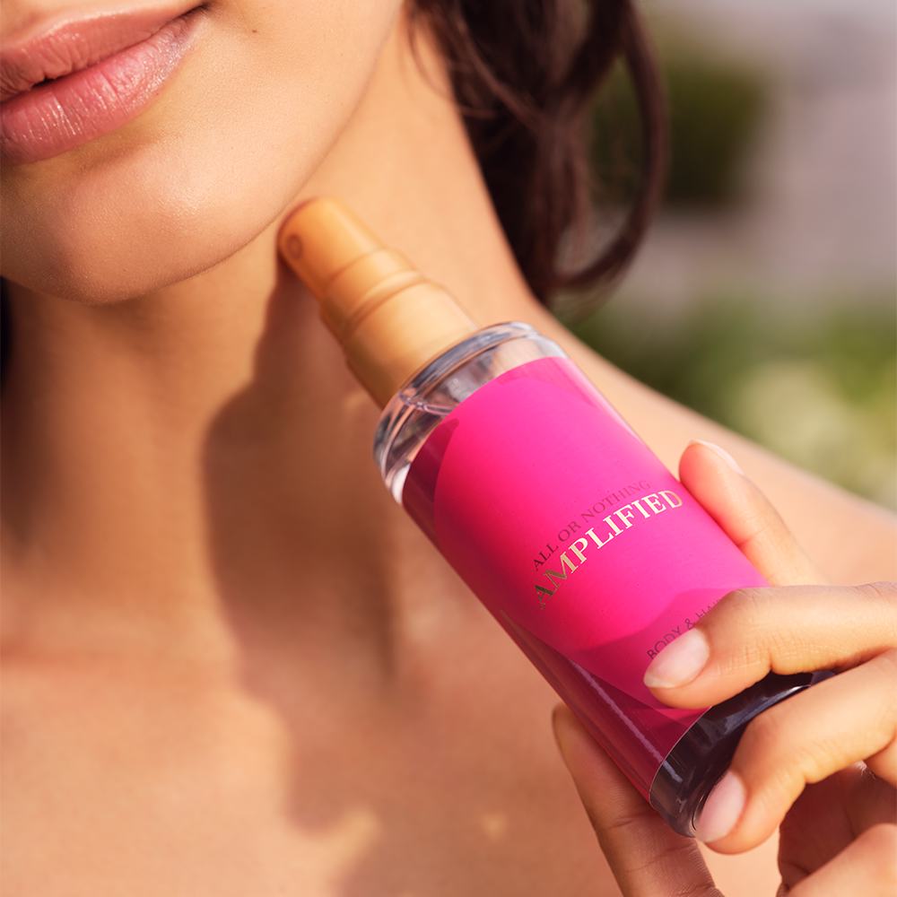 Eine Frau, die ein rosa Spray auf ihren Hals sprüht