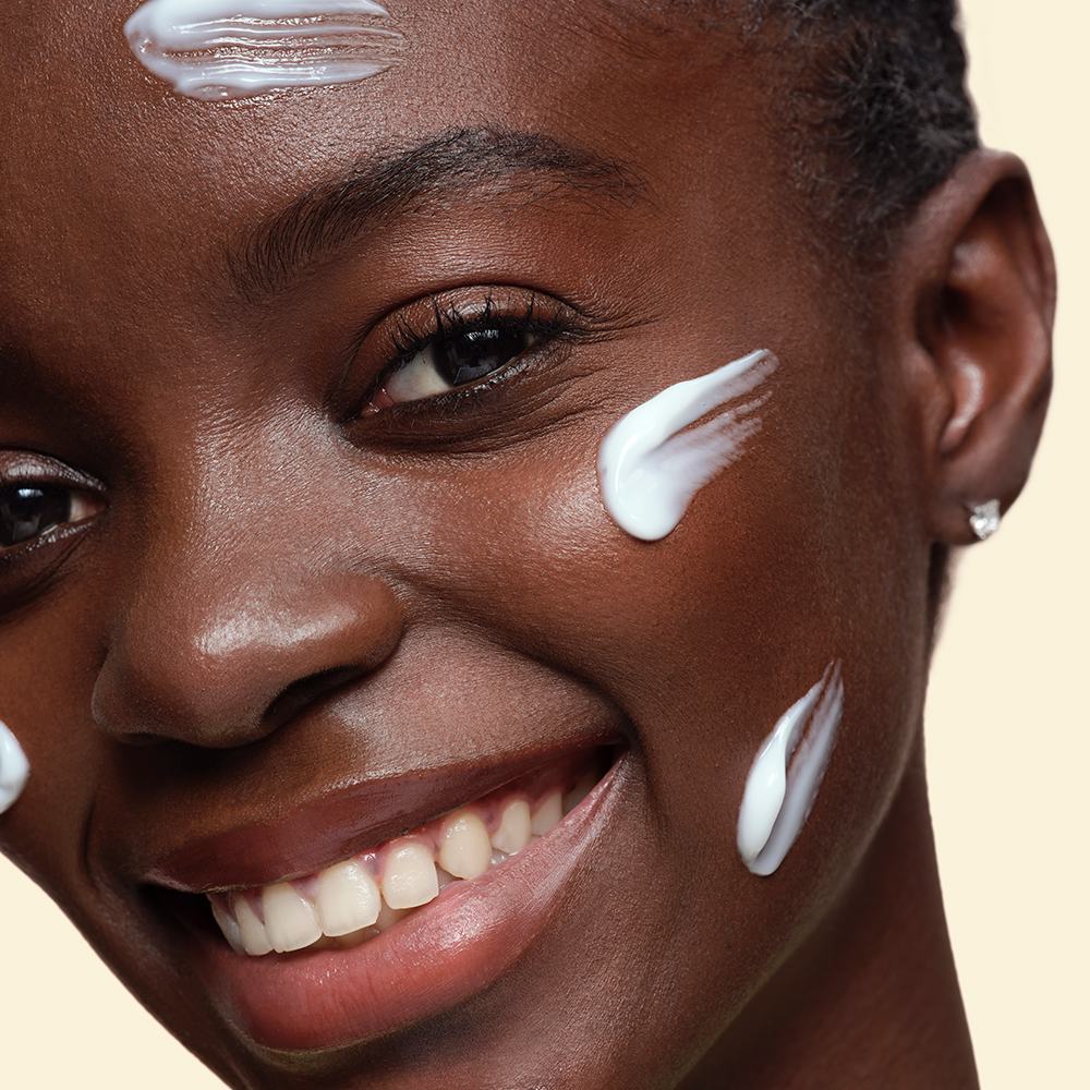 Una mujer sonriendo con crema en la cara