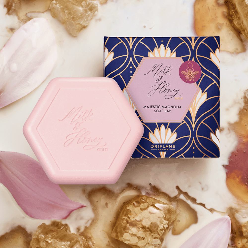 un săpun roz într-o cutie albastră lângă o cutie albastră cu petale de flori aurii și albe