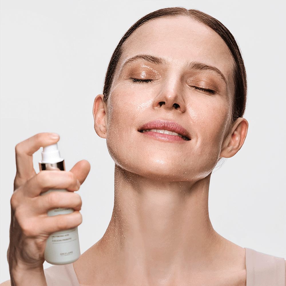 uma mulher com os olhos fechados a segurar um frasco pulverizador