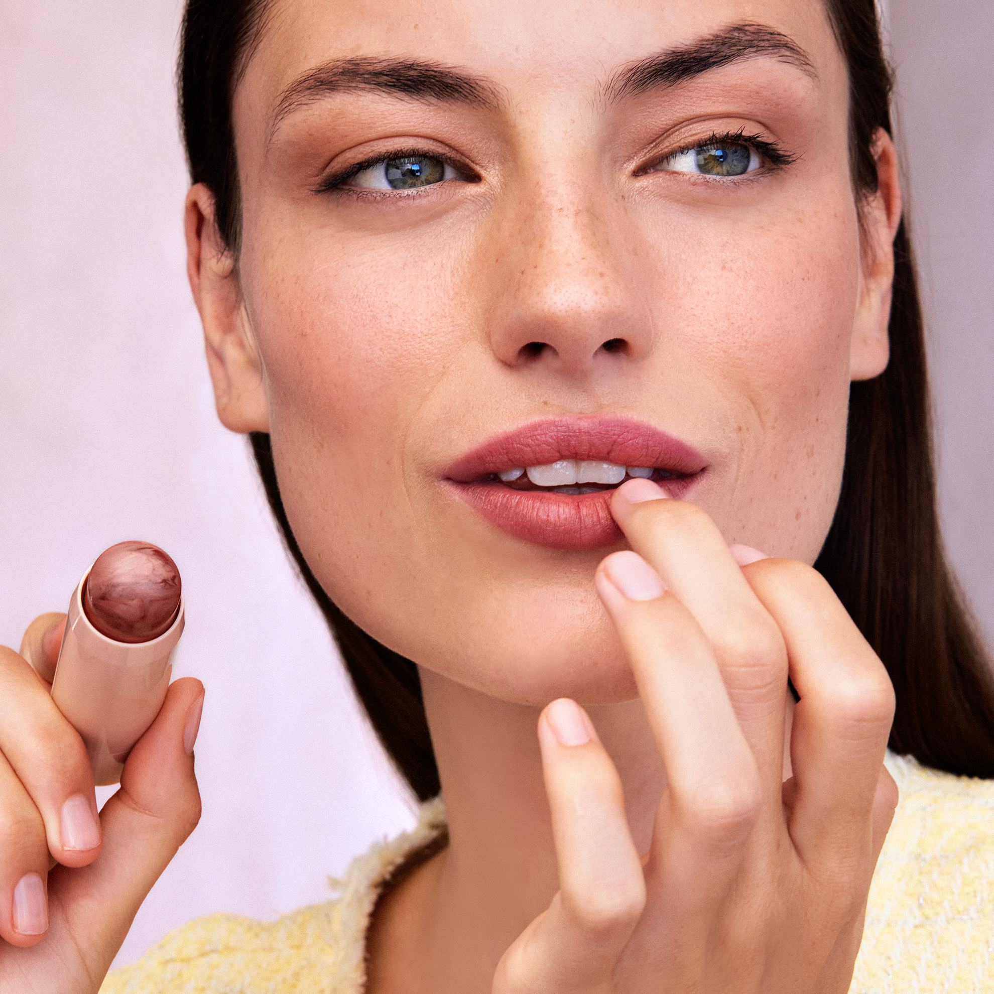 seorang wanita sedang mengaplikasikan lipstik