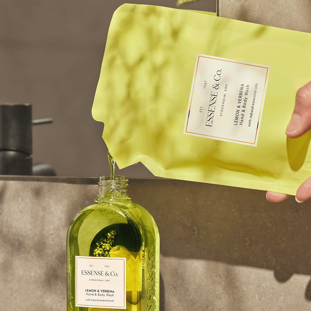 o mână care toarnă un lichid galben într-o sticlă