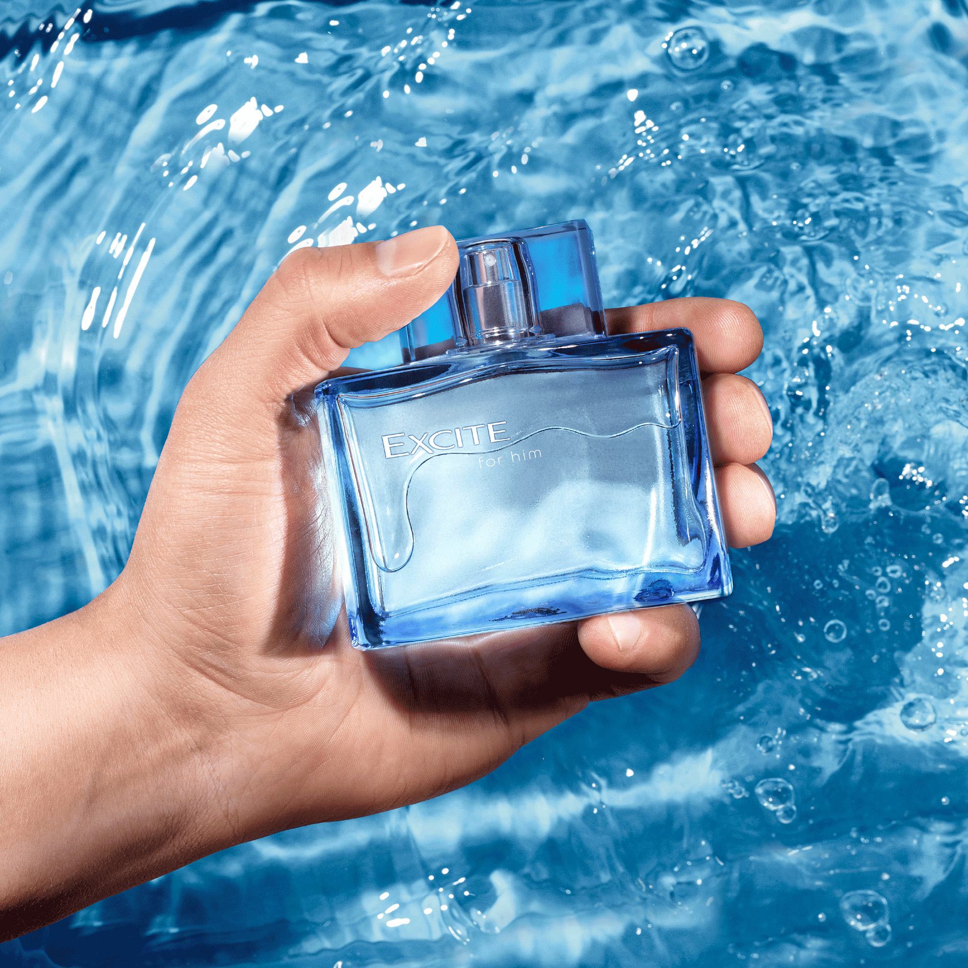 una mano sosteniendo un frasco de perfume en el agua
