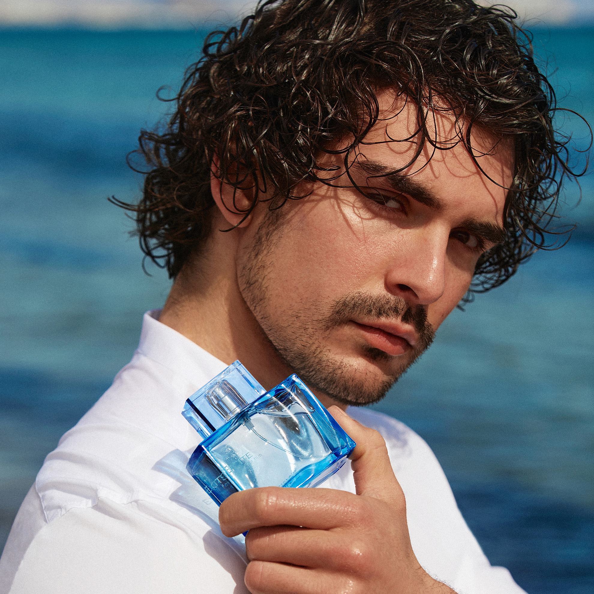 un hombre sosteniendo un frasco de perfume