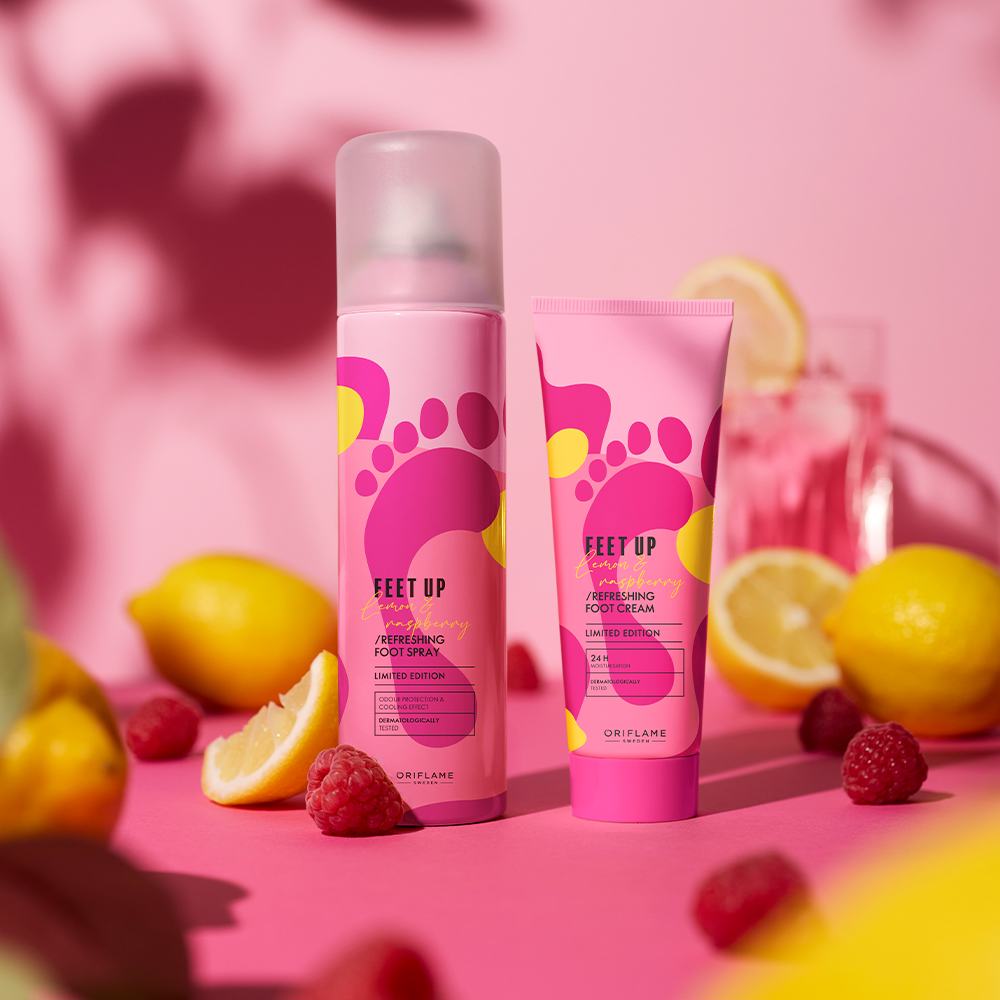 limonlar ve ahududuların yanında duran pembe bir vücut losyonu şişesi
