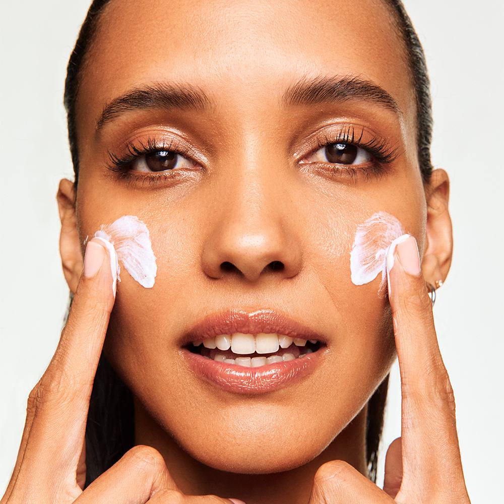 a woman applying cream on her face