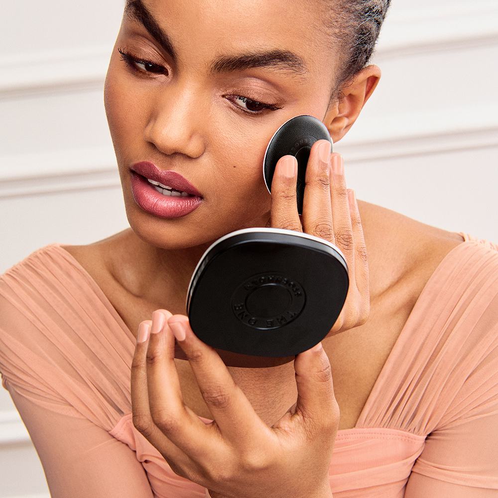 a woman applying makeup with a round black object