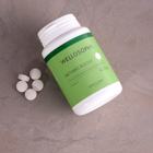 a white bottle with a green label next to white pills