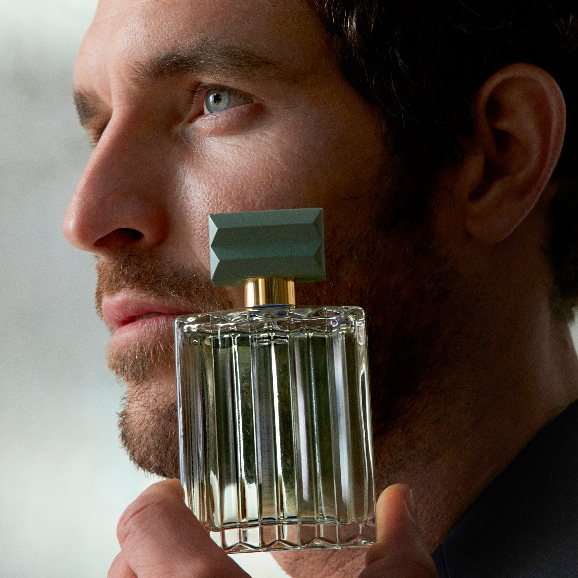 um homem segurando um frasco de perfume