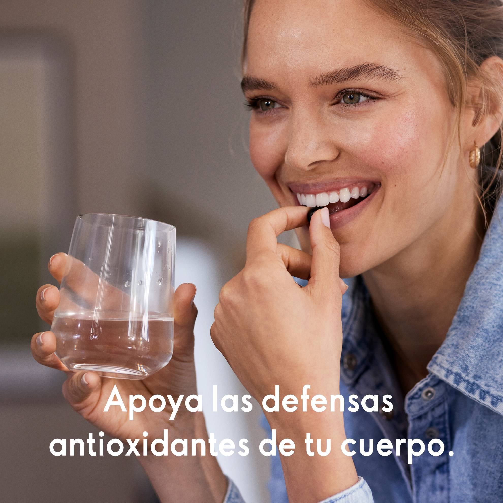 Una mujer sosteniendo un vaso de agua y una pastilla.