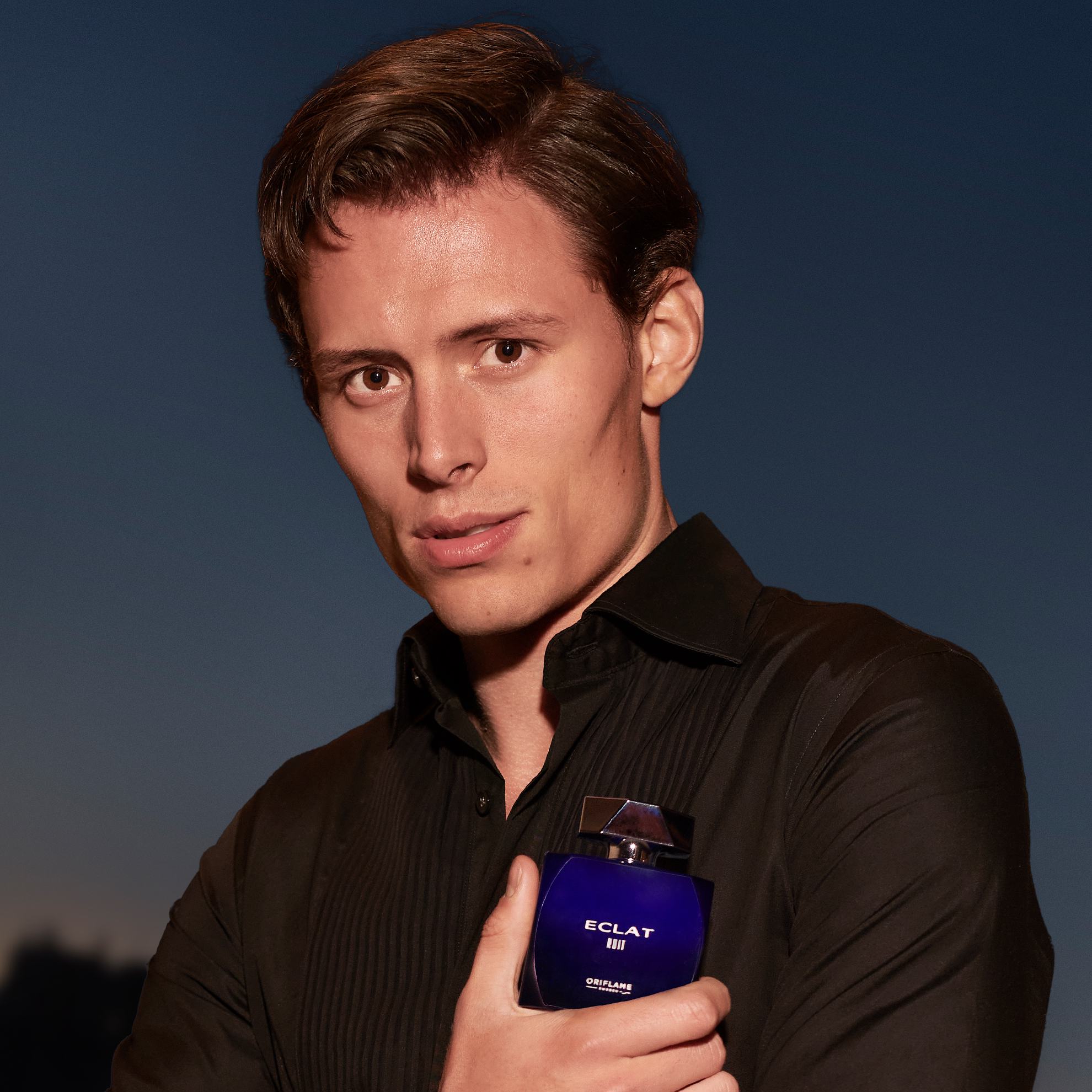 un bărbat ținând o sticlă de parfum