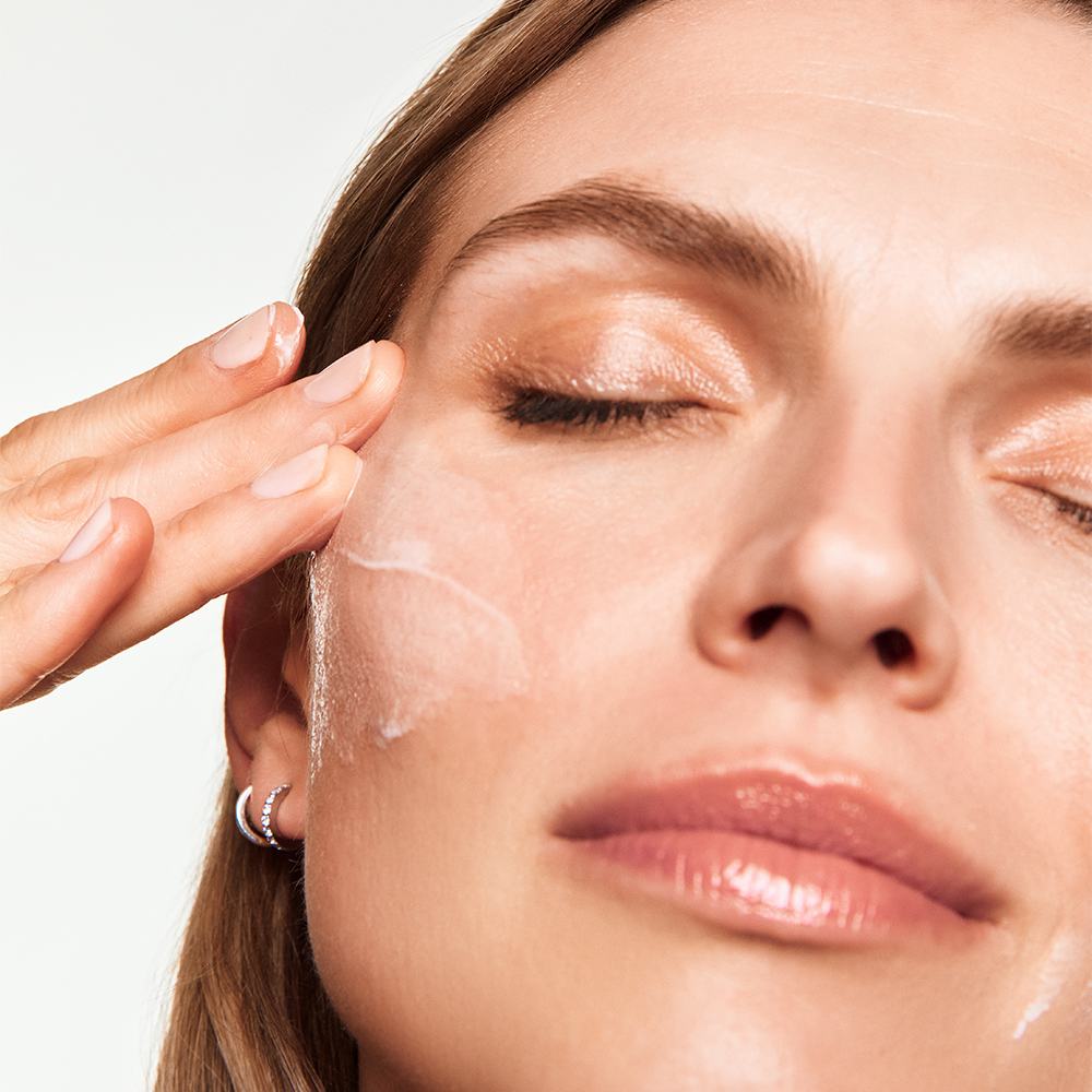 a woman applying cream on her face