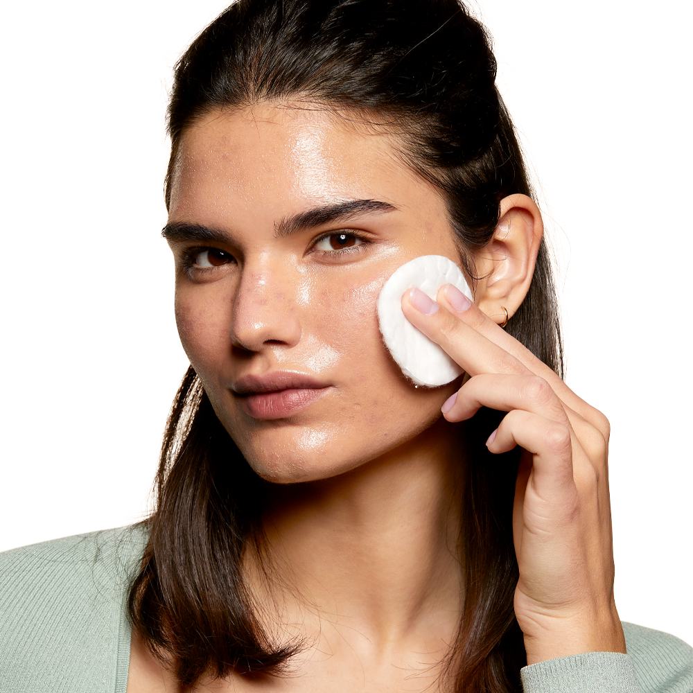 en kvinne som renser ansiktet sitt med en bomullspad