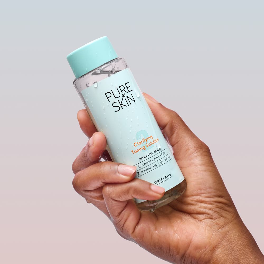 sebuah tangan memegang botol perawatan kulit