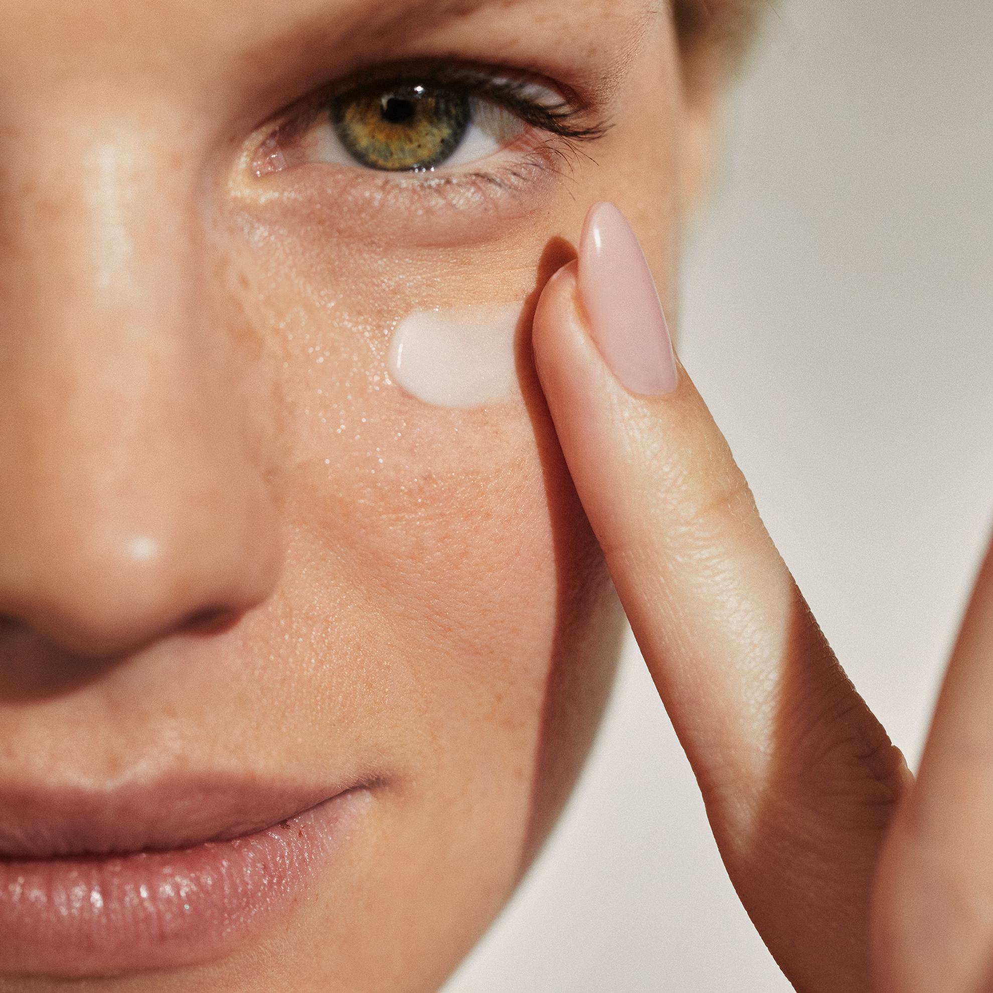 lähiplaan naisest, kes kannab kreemi silmadele