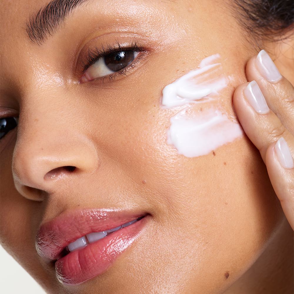 ženska, ki si nanaša kremo na obraz