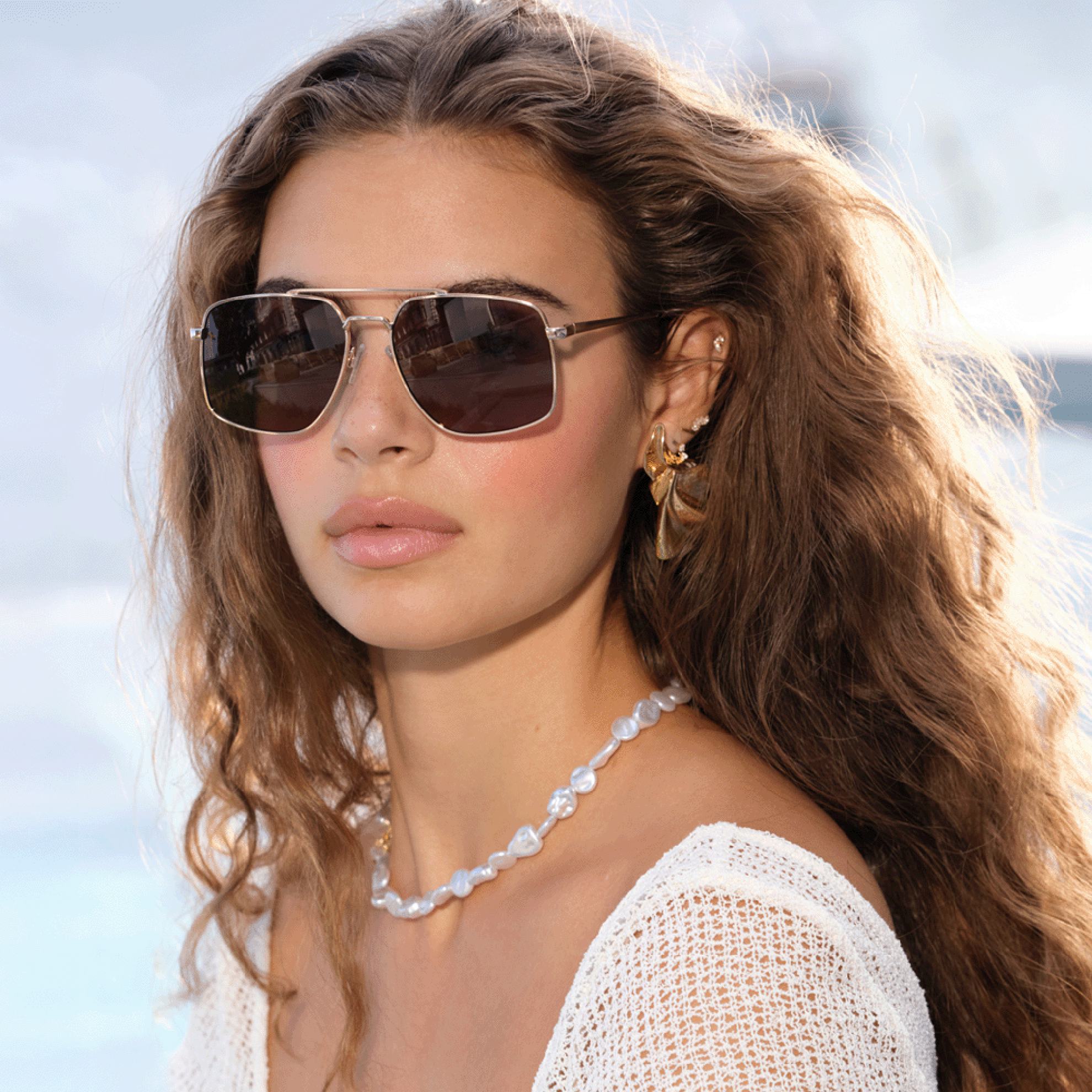 a woman wearing sunglasses and a white shirt