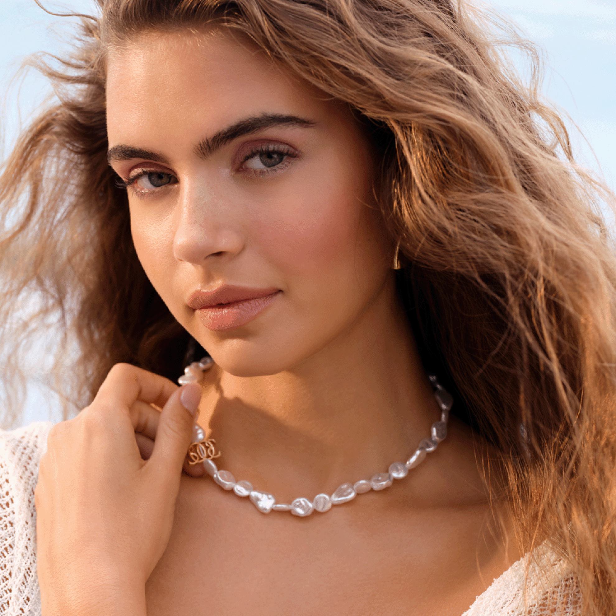 a woman with long hair wearing a pearl necklace